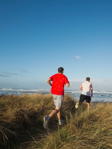 Young adult men running on dune