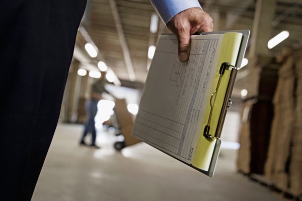 Close up of man holding clipboard in warehouse