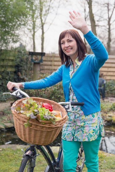 Mature woman with fresh vegetables in bike basket