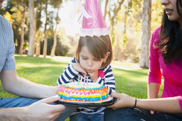 Portrait of happy family in park celebrating daughter's (4-5 years) birthday