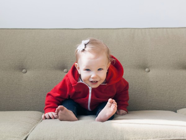 Portrait of baby girl (12-17 months) sitting on sofa