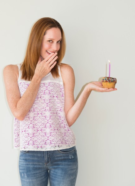 Studio portrait of woman holding birthday cupcake.