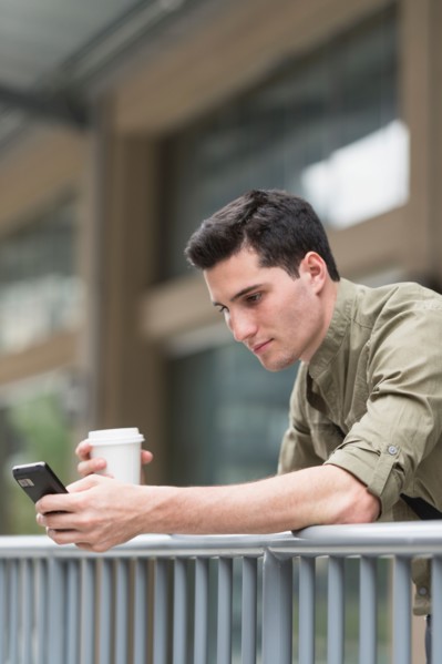 Man drinking coffee and text messaging.
