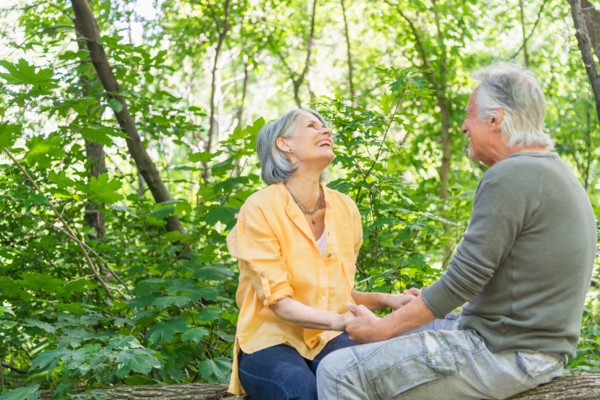 Central Park, New York City. Senior couple sitting on log in forest.