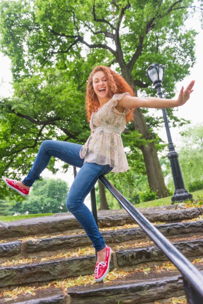 Central Park, New York City. Woman sliding on railing in park.