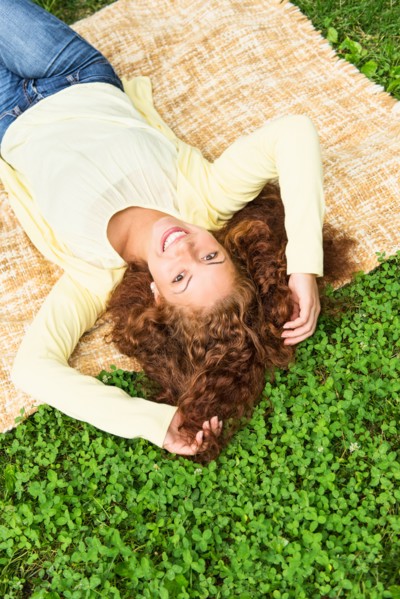 Woman lying on grass in park.