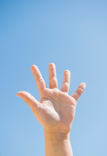 Girl's (8-9) palm against blue sky