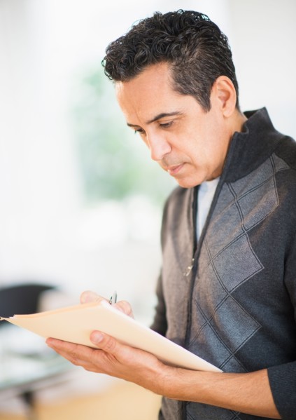 Portrait of man holding documents and writing