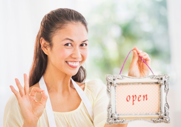 Portrait of mid adult women holding open sign