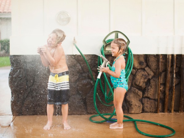 Children (2-3, 6-7) refreshing with garden hose