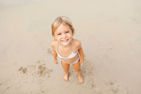 Smiling girl (2-3) on sandy beach