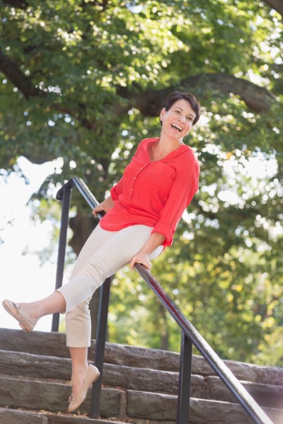 Mature woman sliding down railing in park.