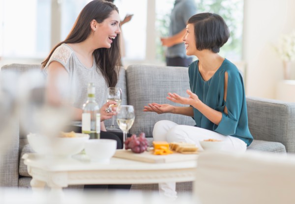 Two friends sitting on sofa and talking.