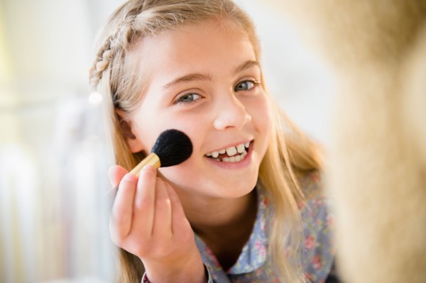 Girl (8-9) applying make-up