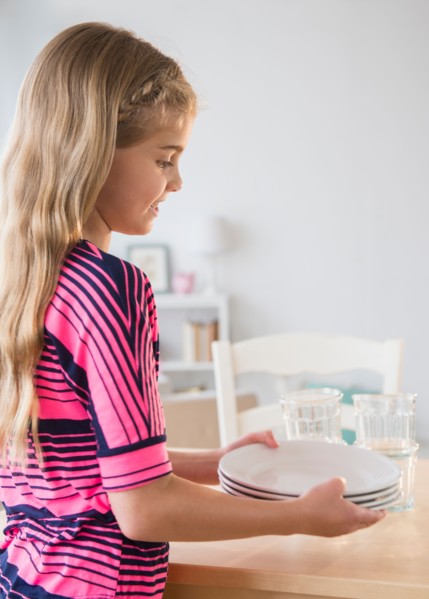 Side view of girl (8-9) holding plates