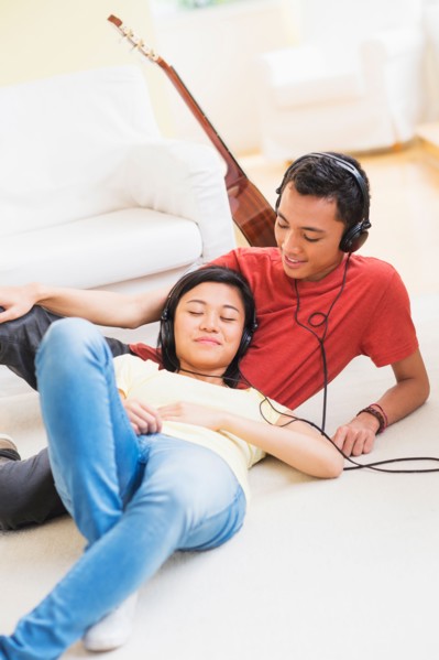 Young woman and man listening music with headphones on