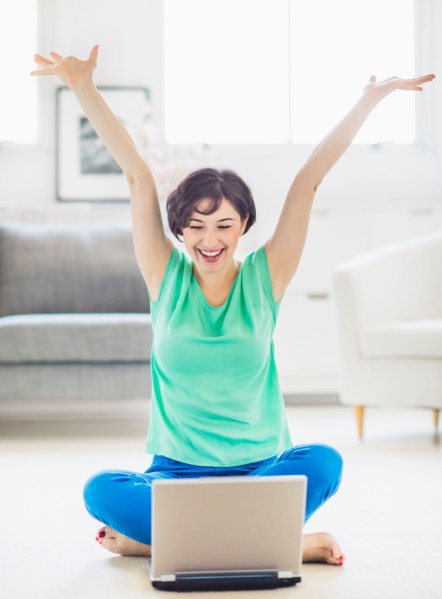 Young woman cheering in front of laptop