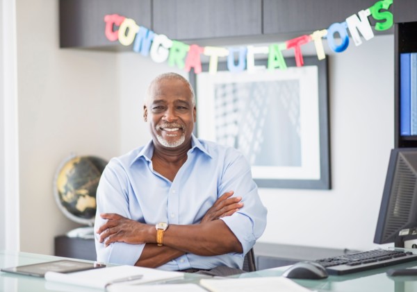 Portrait of man in office, congratulations sign behind