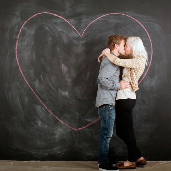 Studio portrait of young couple embracing in front of blackboard