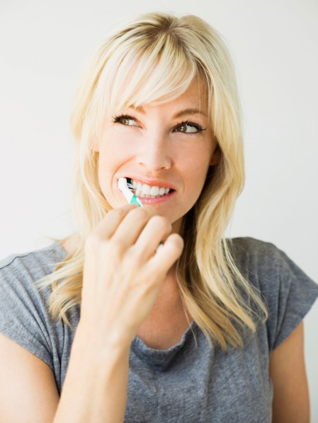 Studio portrait of blonde woman cleaning teeth