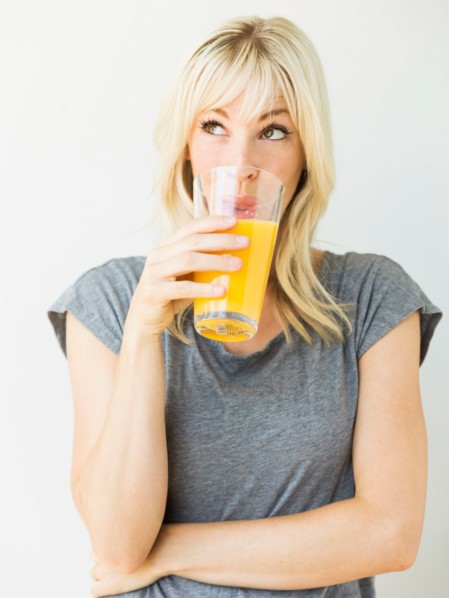 Studio portrait of blonde woman drinking orange juice