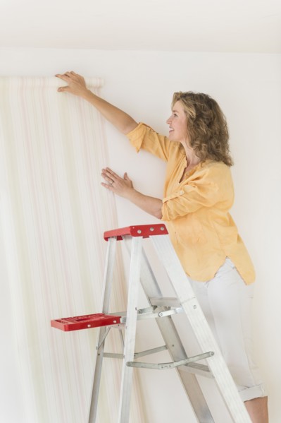 Woman trying out new wallpaper at home.