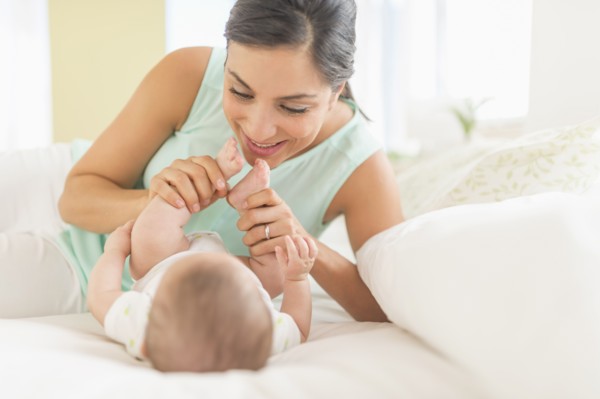 Mother and baby (2-5 months) lying on bed.
