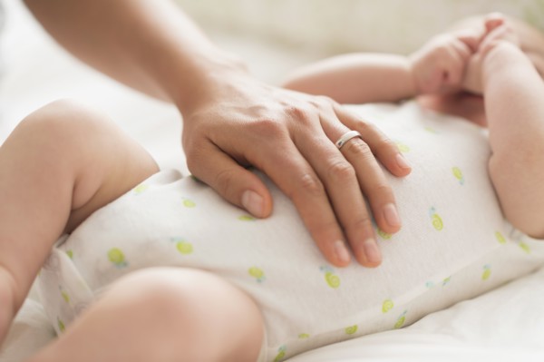 Mother massaging belly of baby boy (2-5 months).