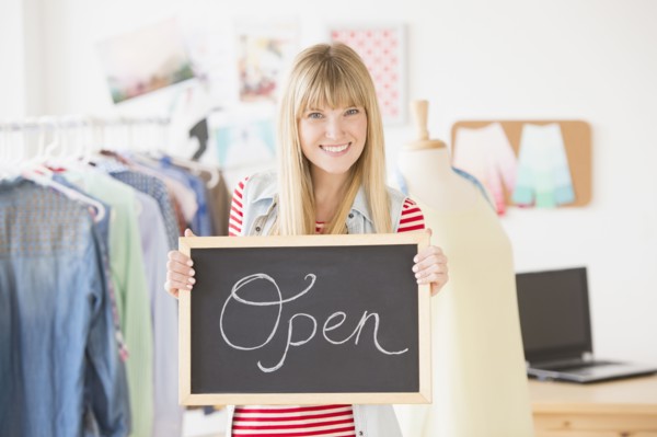 Portrait of female business owner holding open sign.
Photo : Jamie Grill