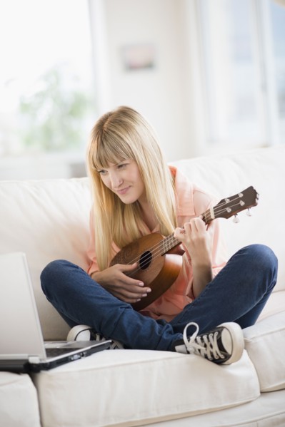 Woman playing ukulele while using laptop.
Photo : Jamie Grill