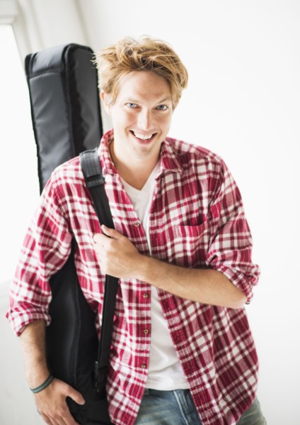 Portrait of man carrying guitar bag.
Photo : Daniel Grill