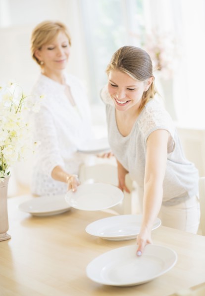 Mother and adult daughter setting table for dinner.
Photo : Daniel Grill