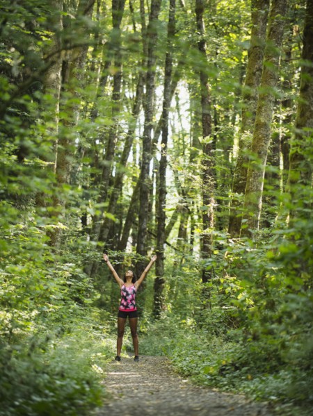 Young women with arms raised in forest. USA, Oregon, Portland.