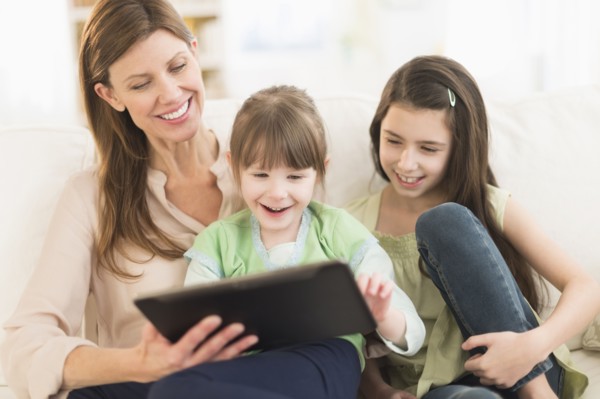 Mother and daughters (4-5, 8-9) using tablet pc.