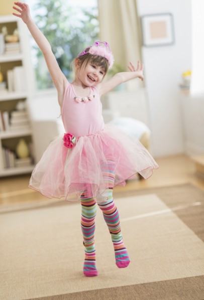 Girl (4-5) wearing tutu dancing in living room.