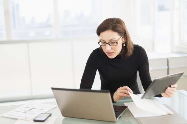 Businesswoman working on laptop and digital tablet.