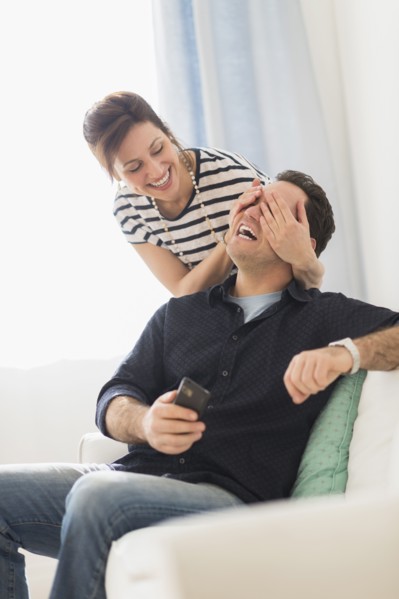 Woman covering man's eyes.
