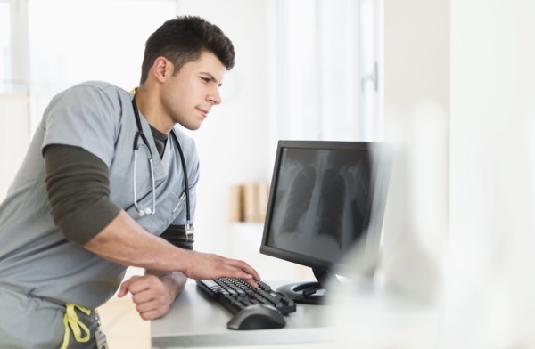 Young man with stethoscope working at computer.