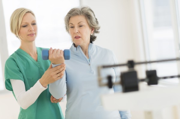 Mature woman exercising with personal trainer.