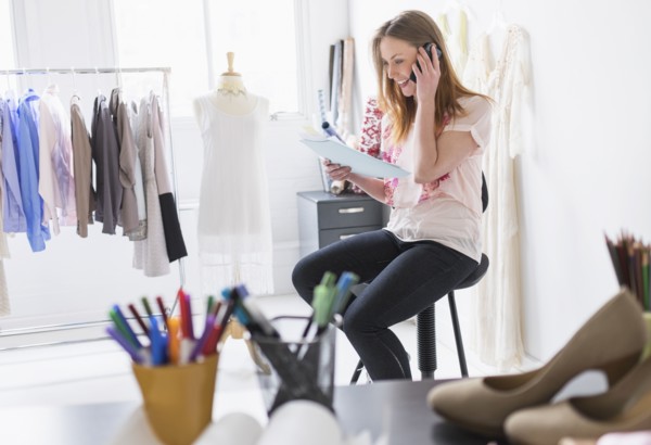 Portrait of female costume designer using mobile phone in studio.
