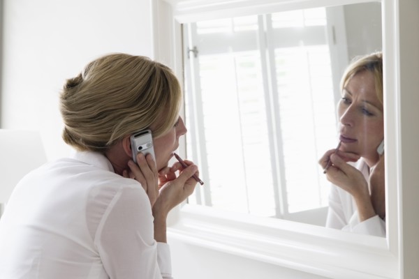 Woman applying make-up and talking on mobile.
Photo : Mark de Leeuw