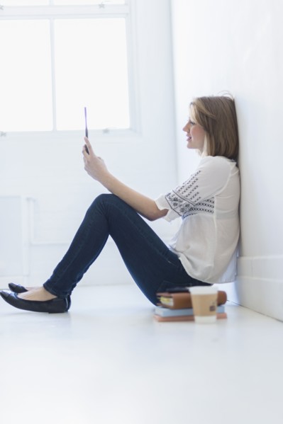 Young woman sitting on floor and using digital tablet.