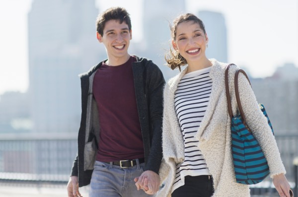 Young couple walking, buildings in background.