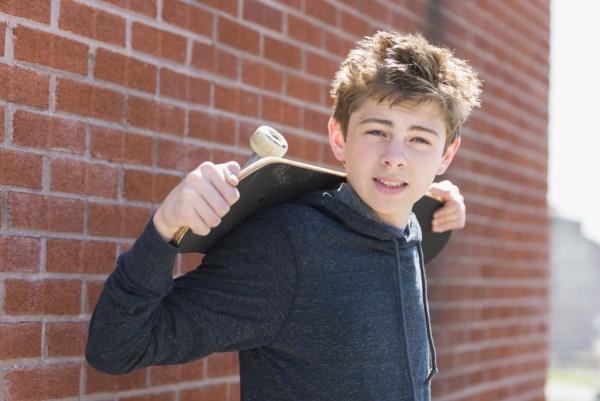Teenage boy (16-17) holding skateboard.