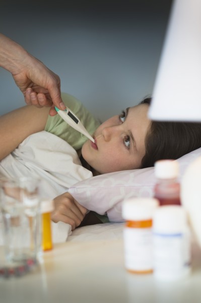Sick girl (8-9) with thermometer in mouth.