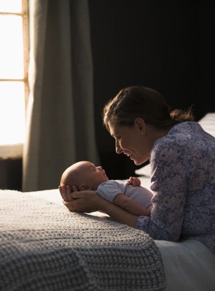 Mother holding baby boy (2-5 months) in bedroom.