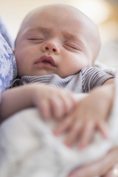 Close up of baby boy (2-5 months) sleeping in mother's arms.