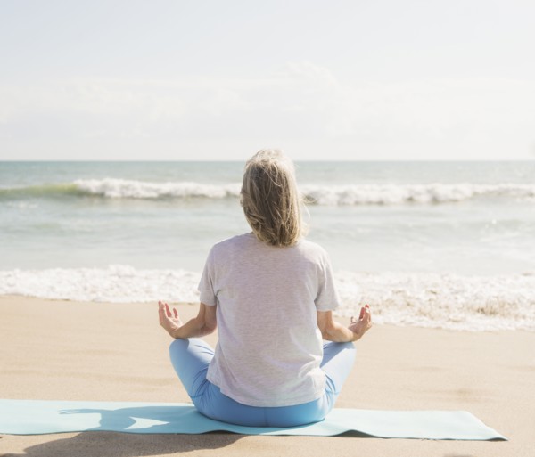 Senior woman practicing yoga on beach.
Photo : Daniel Grill