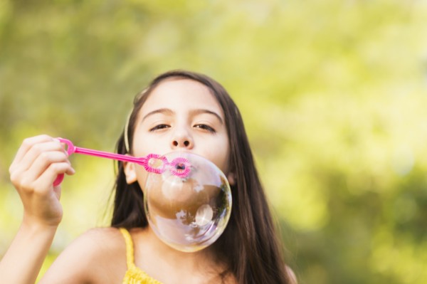 Portrait of girl (8-9) blowing bubbles.
Photo : Daniel Grill