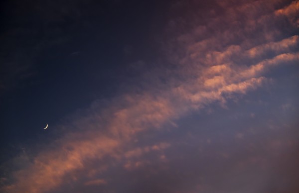 Moon against cloudy sky at sunset.
